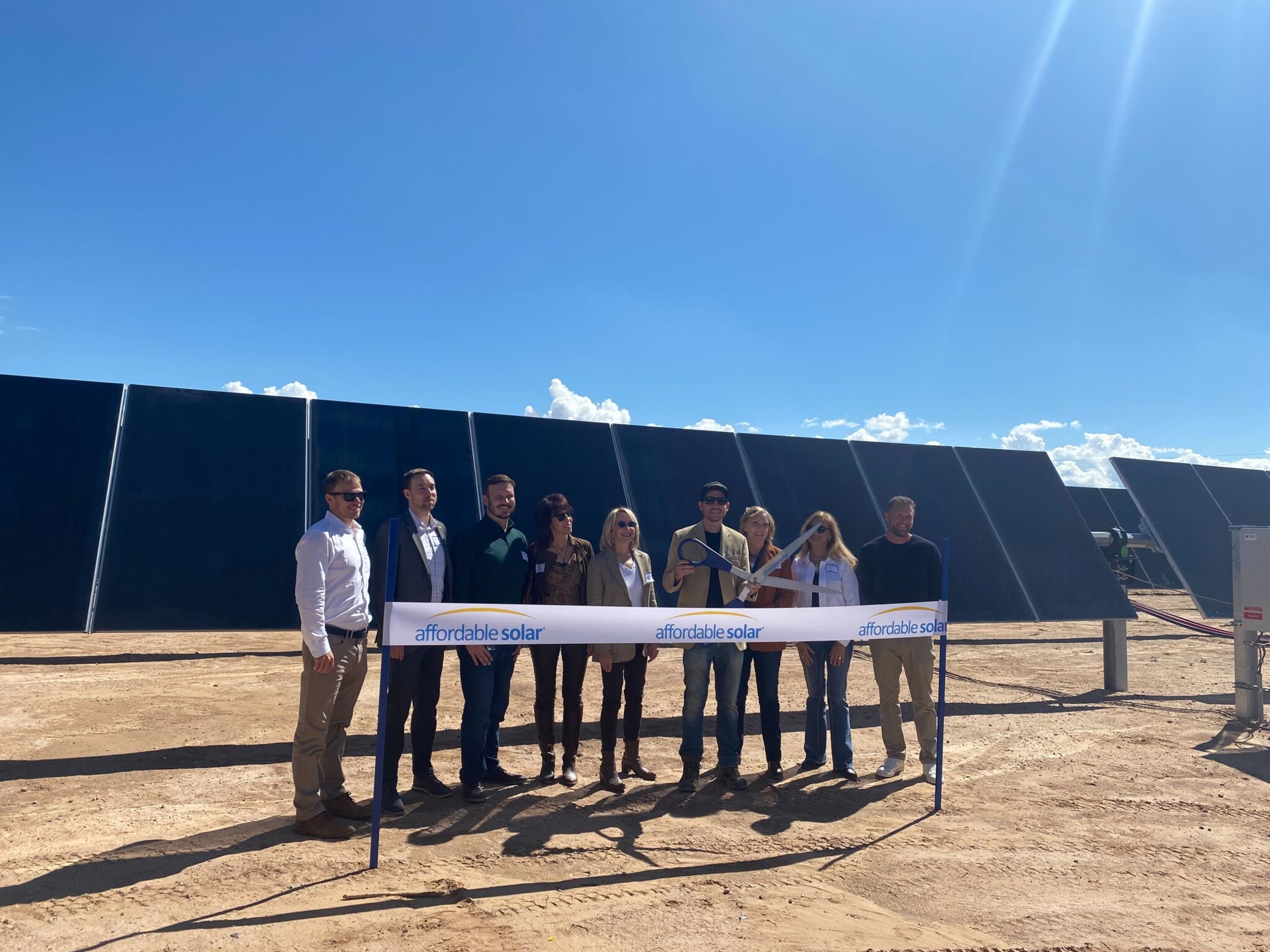 Ribbon cutting in front of completed rows at the Belen community solar project